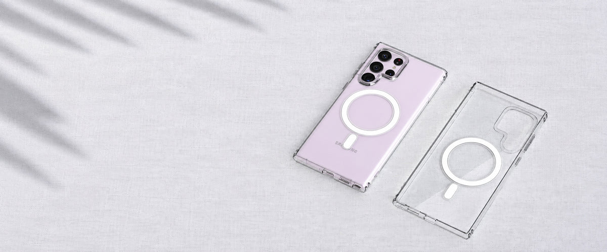 Lavender Samsung phone in a clear magnetic case beside an empty clear case on light fabric.